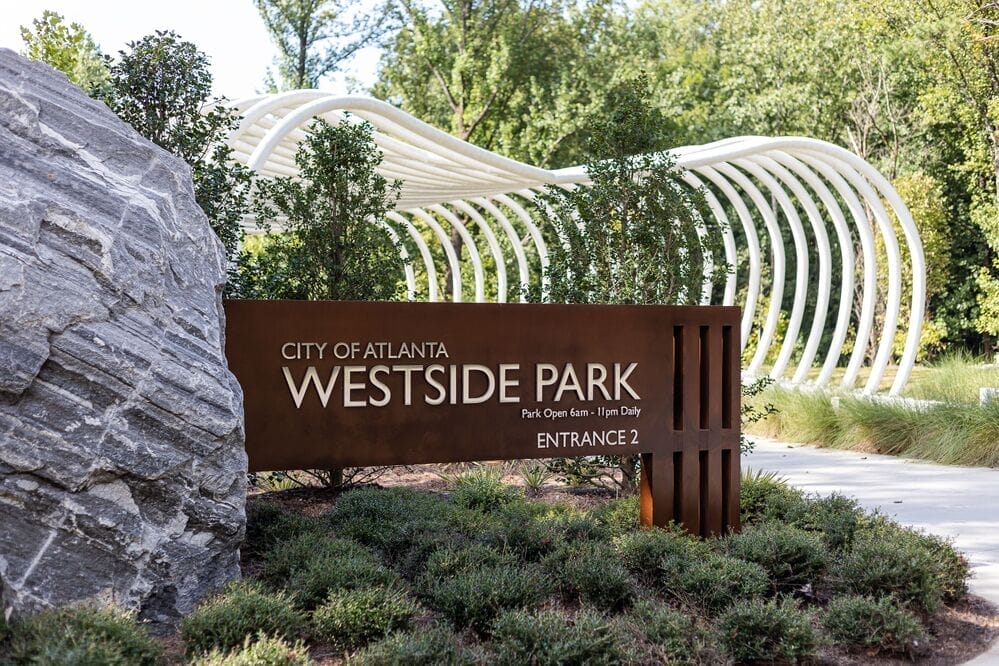 Entrance to Westside Park in Atlanta with sign, greenery, and modern architectural structure with curved white beams.