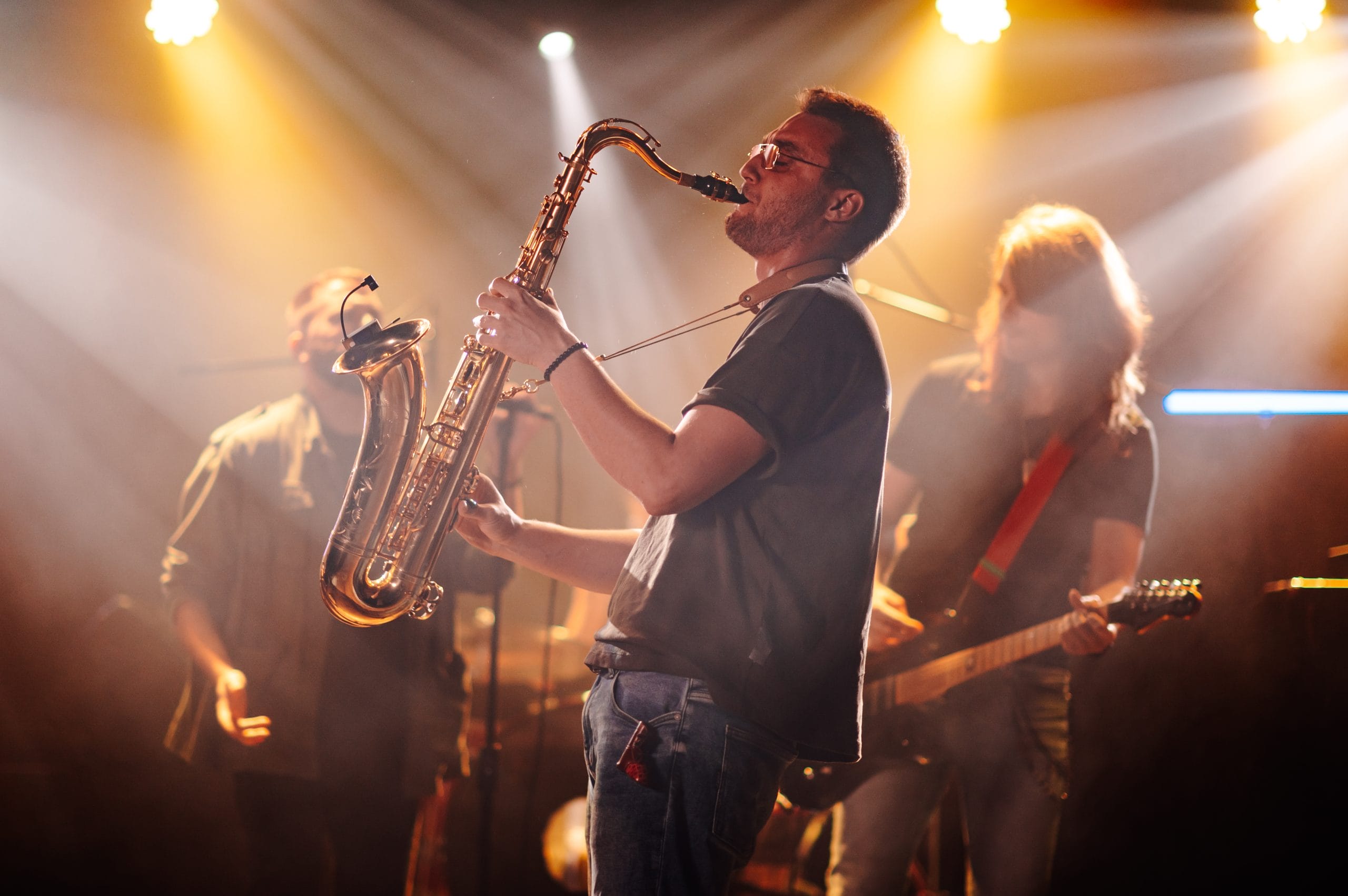 Saxophone player captivating the crowd with a lively performance on a vibrant stage illuminated by orange lights, filling the nightclub with energy and passion