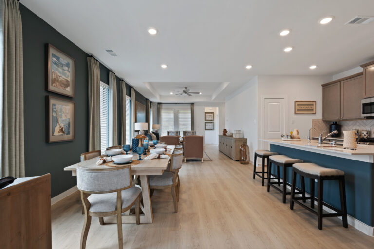 Spacious kitchen and dining space featuring modern lighting, blue island stools, and stylish wall art.
