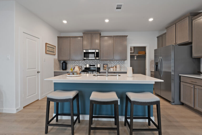 Spacious kitchen with stainless appliances, pendant lighting, and a bold blue island