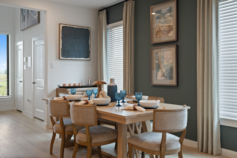 Dining area with a round table, upholstered chairs, and large windows providing natural light in a new home in Rosenberg Texas