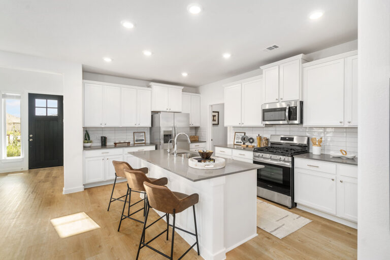 Bright kitchen featuring a central island, bar stools, stainless appliances, and contemporary finishes