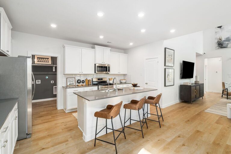 Modern kitchen with stainless steel appliances, quartz countertops, and a center island in a new Rosenberg home.