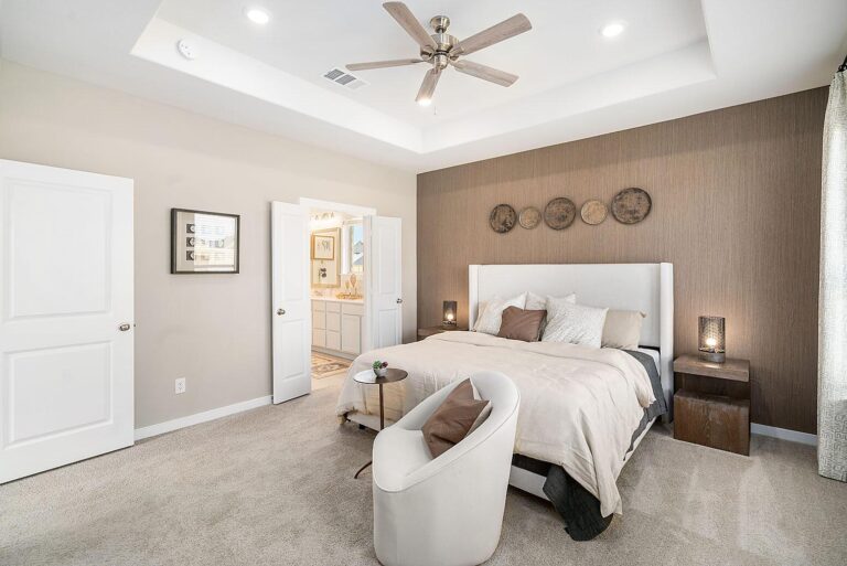 Large primary bedroom with soft neutral tones and a ceiling fan