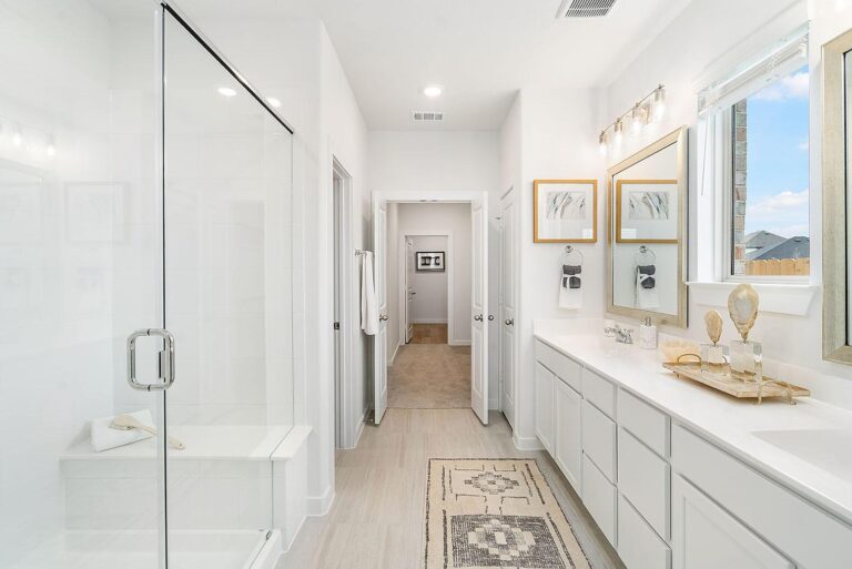 Primary bathroom with beautiful sinks, glass shower, and modern finishes in a new home at Talon Ridge in Rosenberg Texas
