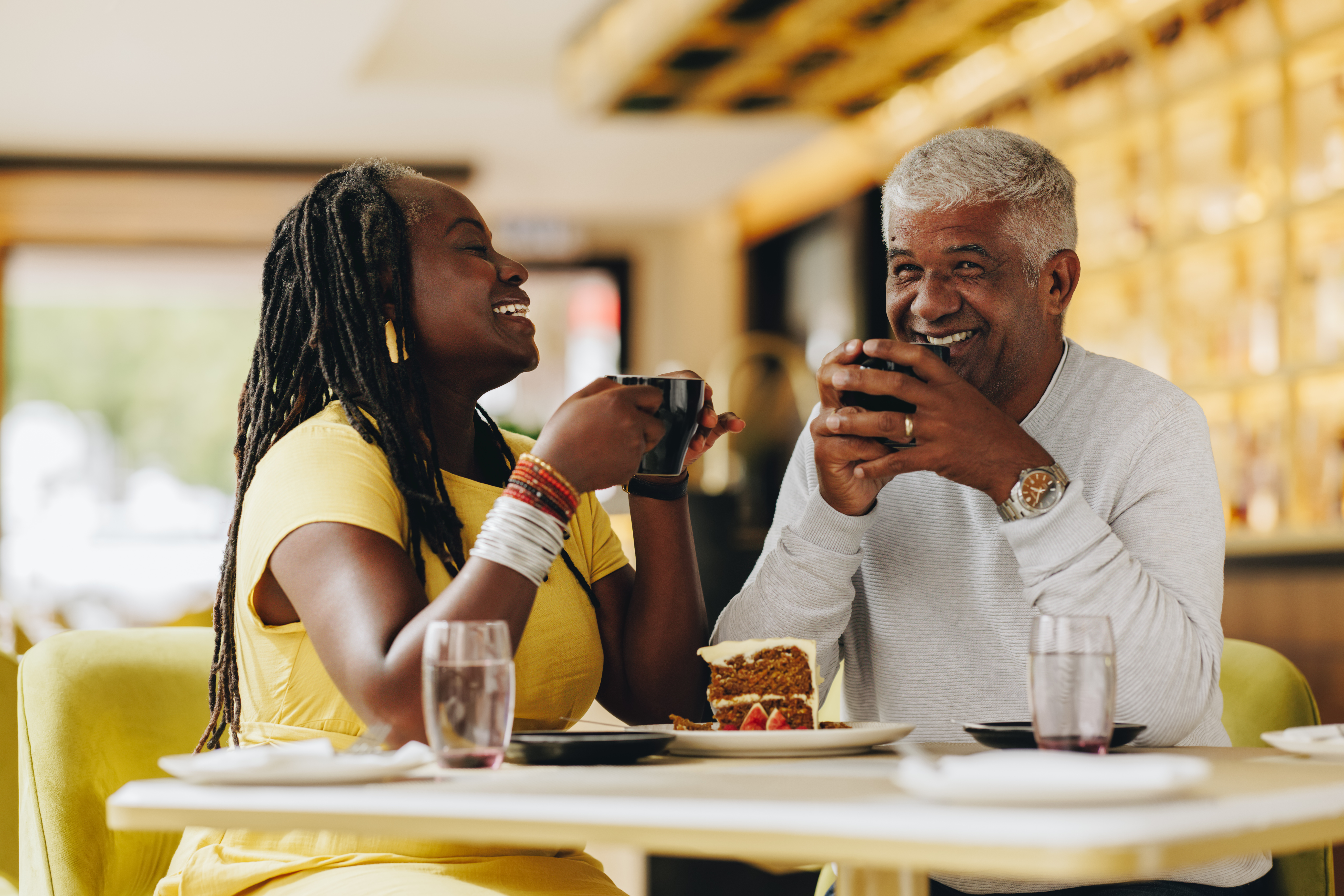 Happy senior couple laughing cheerfully while having coffee together in a cafe. Carefree senior couple having a good time in a restaurant. Mature couple enjoying their retirement together.