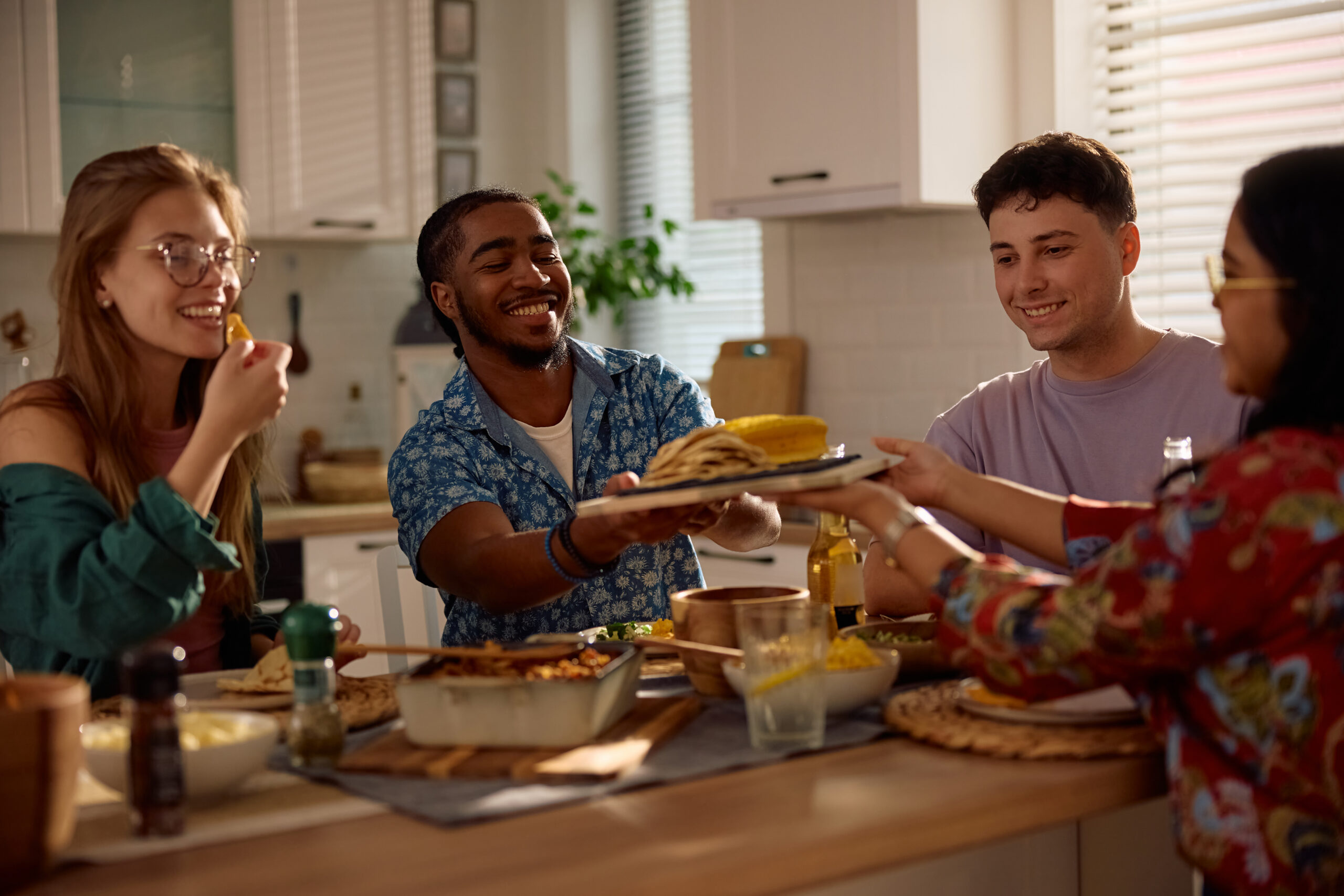 Young happy friends eating Mexican food while gathering at dining table at home.